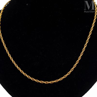 a gold chain necklace on a black mannequin display