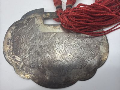 une vieille assiette en argent surmontée d'un cordon rouge