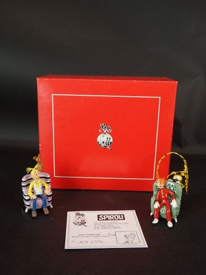 Deux figurines représentant des personnes en costume traditionnel chinois sont assises devant une boîte rouge.