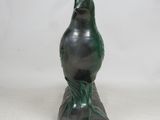 statue of a green bird on a black base on a white background