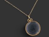 un collier plaqué or avec un pendentif en verre bleu monté sur une chaîne