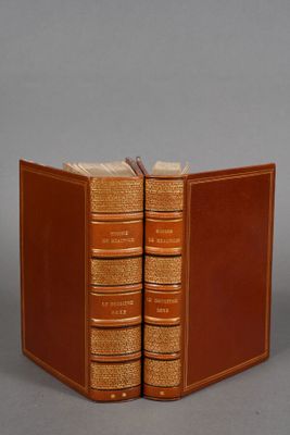 two books are stacked on top of each other on a gray surface