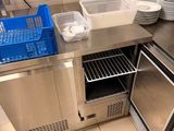 plan de travail en acier inoxydable dans une cuisine professionnelle, sur lequel sont empilés des plats