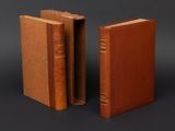two old books sitting side by side on a black surface