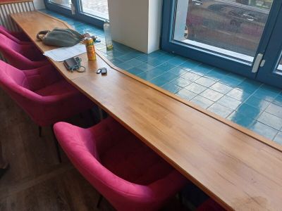 une longue table en bois avec des chaises roses devant une fenêtre