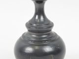 un vase noir posé sur une surface blanche