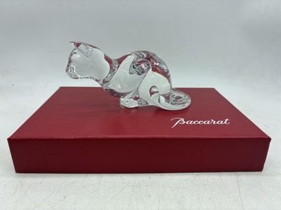 La figurine en verre représentant un chat est posée sur une boîte rouge.