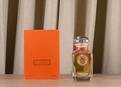 an orange box sitting next to a bottle of perfume on top of a wooden table