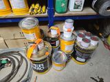 many cans of paint and hoses sitting on the floor