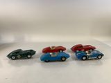 four toy cars are lined up on a white surface