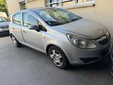 La voiture argentée est garée devant un immeuble, à côté d'une autre voiture garée.