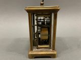 an antique brass clock with a pendulum and a glass case