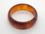 a close up of a brown bracelet on a white surface