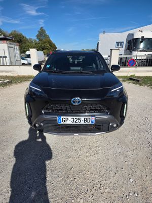 une Toyota RAV noire garée sur un parking en gravier à côté d'un immeuble