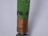 a close up of a green and gold pipe on a white surface