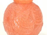 an orange vase that is sitting on a white surface
