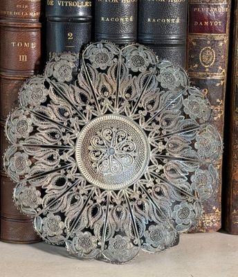 a decorative plate sitting on top of a shelf next to a bunch of books