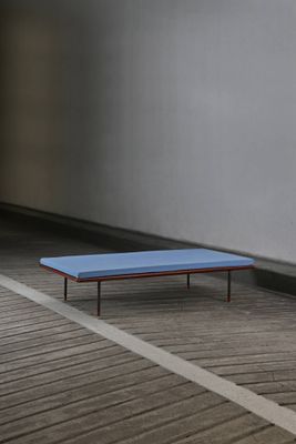 a blue bench sitting on a wooden floor next to a wall