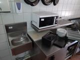 a kitchen with a microwave, sink, and pots hanging on the wall