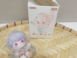 a small plastic doll sitting on a table next to a box