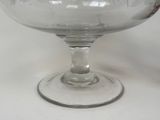 a clear glass bowl with a red handle on a table