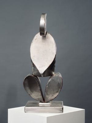 une sculpture métallique représentant une feuille, posée sur un socle blanc