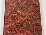 a close up of a red notebook with a swirl design on it