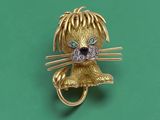 une image représentant une broche en forme de chat en or, avec des yeux en diamant