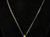 a gold necklace with a diamond pendant on a black mannequin