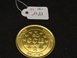 une pièce d'or posée sur une surface noire, avec une étiquette indiquant son prix