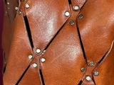 close up of a brown leather bag with rivets and rivets on it