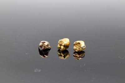 a pair of gold earrings on a reflective surface