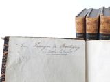 an old book with writing on it sitting next to a stack of books