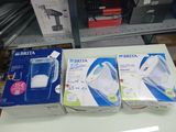 trois boîtes posées sur une table, avec un mixeur dessus