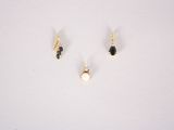 three pairs of gold earrings with black stones on a white surface