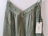 the top of a women ' s green top hangs on a hanger