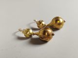 a close up of a pair of gold earrings on a white surface