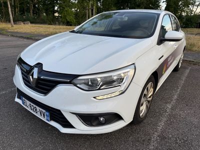 une voiture blanche garée sur un parking, avec des arbres en arrière-plan
