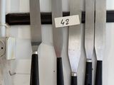 five knives hanging on a wall with a price tag