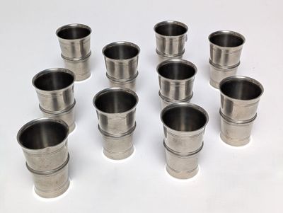 six verres à shot en acier inoxydable posés sur une surface blanche