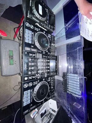 un homme debout à côté d'un imposant équipement de DJ