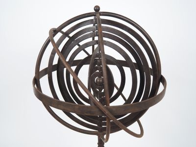 une sculpture métallique représentant un objet tournant posé sur un socle