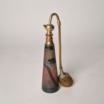 un petit vase muni d'une anse dorée et d'un pinceau
