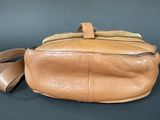 tan leather purse with strap on a black background