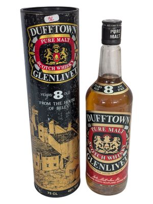 une bouteille de whisky posée à côté d'un carton sur une surface blanche