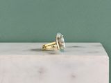 une image représentant une bague en or sertie d'une topaze bleue, posée sur un bloc de marbre