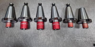 six different types of drill heads are lined up on a metal surface