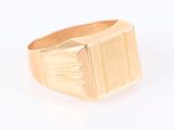 une image d'un gros plan d'une bague en or sur une surface blanche