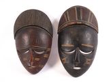 pair of african carved wooden masks on a white background