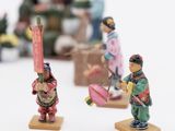 small figurines of asian people standing on small wooden bases